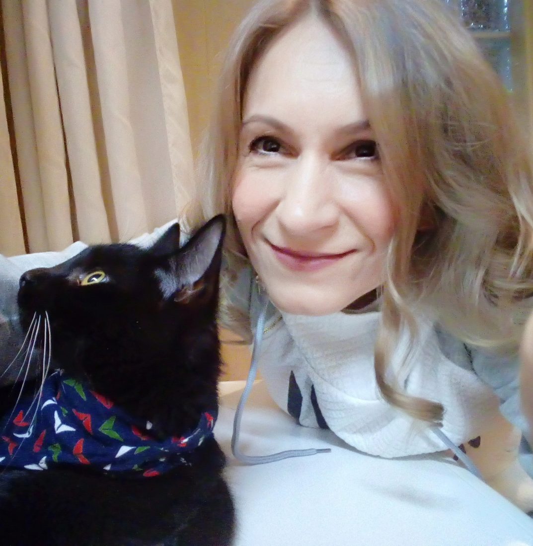 Edit Szóráth smiling cheek to cheek with her black cat in a patterned bandana